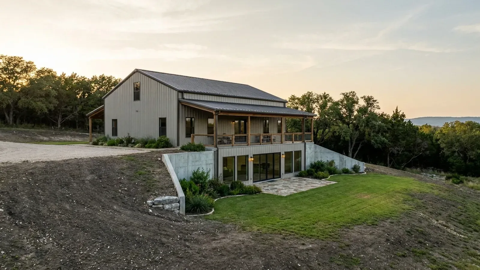 A barndominium with a walkout basement built into a sloping lot, the lower level opening onto a patio at grade.